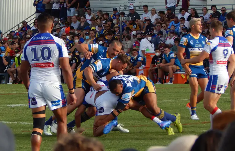 Two Parramatta defenders drive a Newcastle ball-carrier into the turf in front of a packed grandstand, 2021 NRL finals